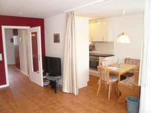 cocina y sala de estar con mesa y TV en App-Hoelscher-21, en Westerland