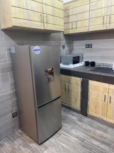 a stainless steel refrigerator in a kitchen with wooden cabinets at Appartement Kekely in Lomé