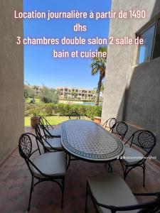 una mesa y sillas en un patio en Prestigia 3 chambres piscine, en Marrakech