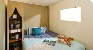 Cette petite chambre comprend un lit et une étagère. dans l'établissement Camping Onlycamp Pierre & Sources, à Volvic