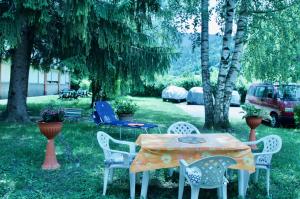 una mesa y sillas en un patio con árboles en Al Sole di TSS' - Cozy Apartment a 20 Metri dal Lago di Caldonazzo - Perfetto per coppie a Calceranica al Lago, en Calceranica al Lago