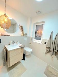 ein Badezimmer mit einem Waschbecken, einem WC und einem Spiegel in der Unterkunft Maison Saarschleife Mettlach in Mettlach