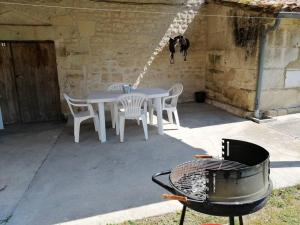 a patio with a table and chairs and a grill at Maison charentaise in Pons