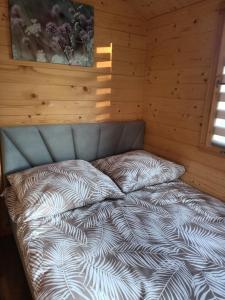 1 dormitorio con 1 cama en una pared de madera en Domek nad stawem, en Golczewo
