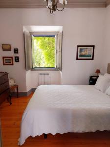 a bedroom with a large white bed and a window at Vila Casa Do Sobral in Óbidos