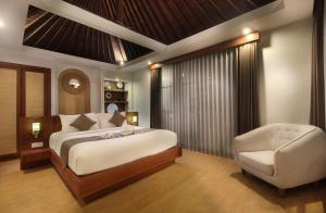 a bedroom with a bed and a chair at Sudha Villa Bali Anyelir in Seminyak