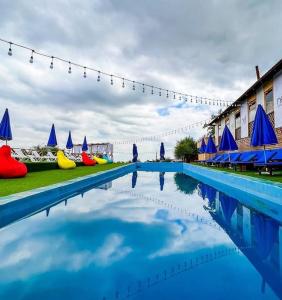 duży błękitny basen z niebieskimi parasolami w obiekcie Panorama Hills w mieście Ałma-Ata