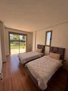 1 dormitorio con 2 camas y ventana grande en Prestigia 3 chambres piscine, en Marrakech