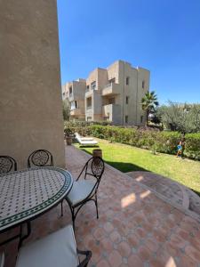 un patio con mesa y sillas y un edificio en Prestigia 3 chambres piscine, en Marrakech