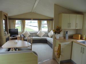 a caravan kitchen and living room with a couch and a table at Coral Beach : The Richmond:- 6 Berth, Blow heated in Ingoldmells