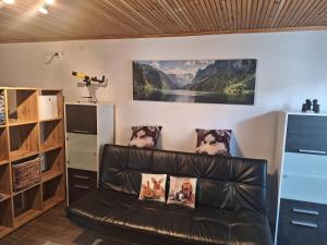 a leather couch in a room with a picture of dogs on the wall at Apartment Tonica in Lokve