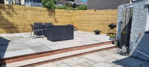 a patio with two chairs and a table in front of a fence at Viaduct View - Cefn Coed in Merthyr Tydfil