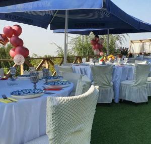 a table with white tables and chairs and a blue umbrella at Panorama Hills in Almaty