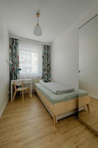 1 dormitorio con cama, mesa y ventana en Apartamenty MM - Rzeźniczaka, en Zielona Góra
