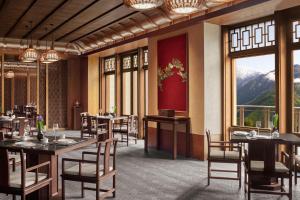 a dining room with tables and chairs and windows at Rissai Valley, a Ritz-Carlton Reserve in Jiuzhaigou