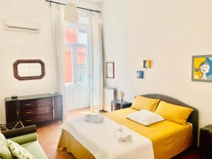 a bedroom with a yellow bed with two towels on it at San Gregorio Luxury Apartments in Naples
