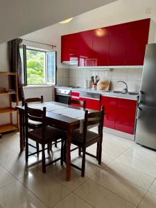 コルチュラにあるApartmani Lukaのキッチン(赤いキャビネット、テーブル、椅子付)