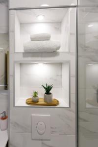 a white bathroom with two potted plants on a shelf at Apartments Beach Side Brela in Brela