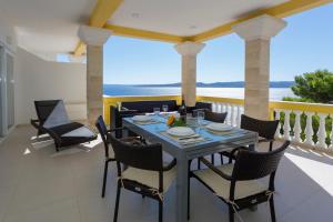 Apartments Beach Side Brela في بريلا: طاولة وكراسي على شرفة مطلة على المحيط