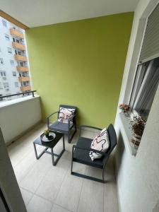 uma varanda com 2 cadeiras, uma mesa e uma parede verde em Novi Sad Apartman em Novi Sad