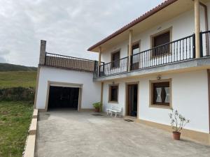 a white house with a balcony and a driveway at J. Casa con vistas en Lira - Carnota in Lira