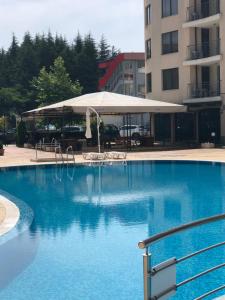 ein großer blauer Pool mit einem weißen Regenschirm in der Unterkunft AVALON, Apartment C102 in Sonnenstrand