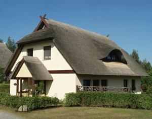 uma casa com um telhado de palha e um alpendre em Zum Froschkönig em Ahrenshoop