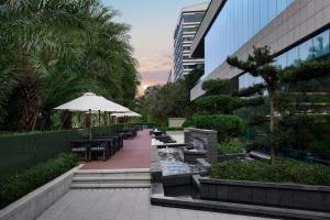 un patio con mesas y sombrilla y un edificio en Courtyard by Marriott Xiamen, en Xiamen