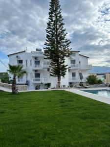 a large white building with a tree next to a pool at Cost Mari Almyrida New by ZAGO Boutiqe hotels in Almyrida