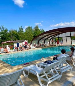a group of people laying in lounge chairs by a swimming pool at Grand mobil home exposé sud, 2 salles de bain in Onzain
