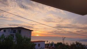 a sunset in the sky with a building at Mihal Suites in Sarandë