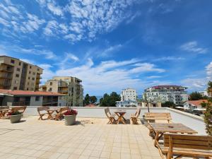 un patio con mesas y sillas de madera y un cielo azul en Horizonti Blu en Shëngjin