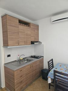 uma cozinha com armários de madeira, um lavatório e uma mesa em Horizonti Blu em Shëngjin