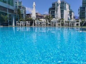 a large swimming pool with chairs and tables and buildings at F 207 Primorsko del Sol - просторно студио с кухня in Primorsko