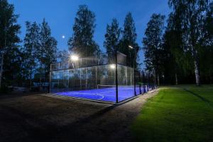 a glass house with a tennis court at night at Saunamäki Resort - Lux Villa in Salo