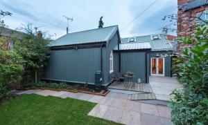 a black shed with a deck in a yard at CHESTER'S ONLY TIN CHAPEL - UNIQUE, SPACIOUS 2 BEDROOMS, GARDEN AND FREE PARKING in Chester