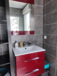 een badkamer met een rode wastafel en een spiegel bij Chambre et salle d'eau dans dépendance 20 m2, vélos in Les Sables-dʼOlonne
