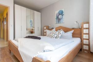 een slaapkamer met een groot bed met witte lakens bij Haus-des-Kurgastes-Wohnung-4 in Heiligenhafen
