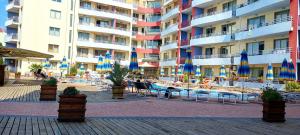 a large building with tables and chairs and umbrellas at Central Plaza - Studio - Sunny Beach in Sunny Beach