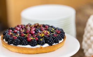 a cake with berries on top on a white plate at Donna Carmela Resort & Lodges in Riposto