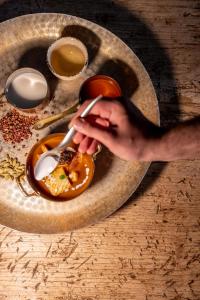 a person holding a spoon and a plate of food at Donna Carmela Resort & Lodges in Riposto
