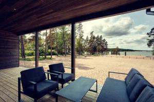 a patio with chairs and a table and a view of a beach at Saunamäki Resort - Beachfront in Salo
