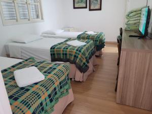 Habitación con 3 camas y mesa con encimera. en Taufik Hotel, en Río Grande