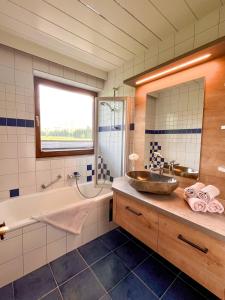 ein Badezimmer mit einem Waschbecken, einer Badewanne und einem Spiegel in der Unterkunft Apartmenthaus Brigitte in Leutasch