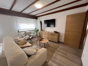 a living room with a couch and a tv and a table at Tu Piso en Portonovo in Portonovo