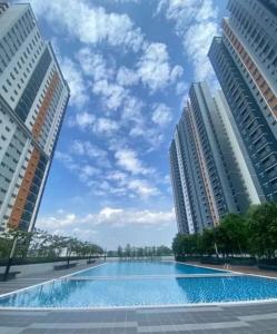 a large swimming pool between two tall buildings at Qilayna guest room in Sepang