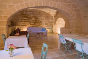a dining room with tables and chairs and a stone wall at Villa Romasi in Leuca