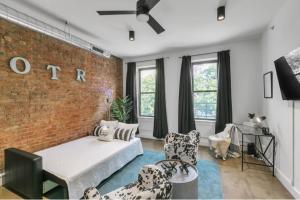 a living room with a brick wall and a bed and chairs at Urban Paradise in OTR - Beautiful New Condo In Historic Building With Downtown Views! condo in Cincinnati