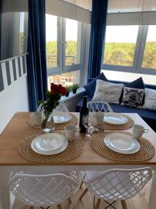 a dining room table with plates and flowers on it at Apartamenty Piaskowe Wypoczynkowa 3 in Rowy