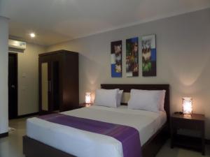 a bedroom with a large bed with two lamps at Mansu Hotel and Spa Legian in Kuta